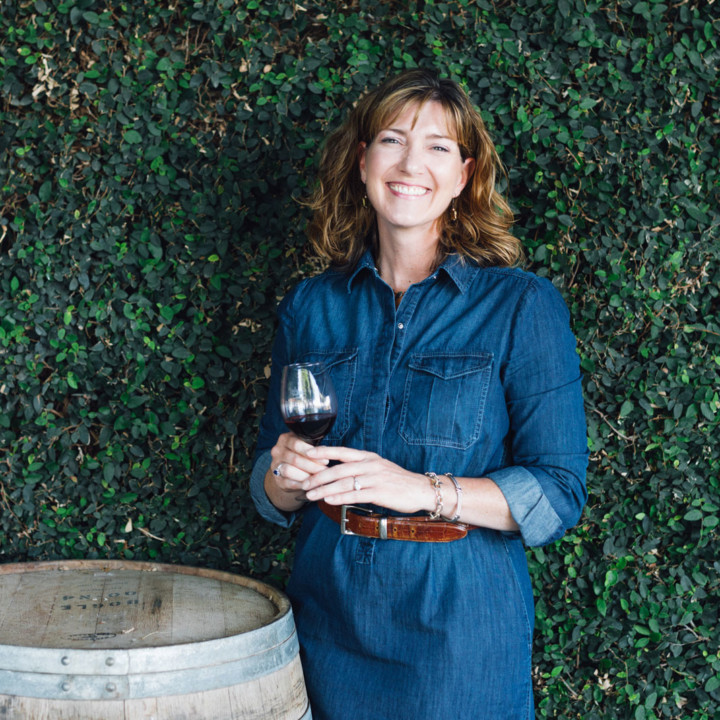 Woman standing next to wine barrel drinking wine